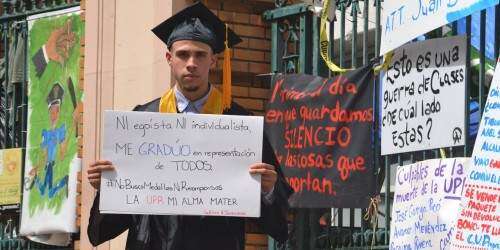 Joven vestido de graduando se manifiesta frente a portones de la UPR-RP